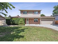 Charming two-story home with manicured lawn, brick accents, and attached garage on a sunny day at 8445 Lamar Dr, Arvada, CO 80003