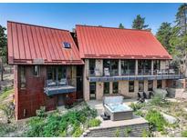 Stunning modern home with a red roof, stone and metal siding, balconies, and a hot tub with mature landscaping at 116 Ramona Rd, Golden, CO 80403