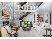 Bright and airy living room featuring a stone accent wall, fireplace, and open staircase at 2224 W 37Th Ave, Denver, CO 80211