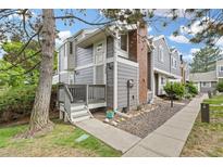 Charming townhome with gray siding, a brick chimney, and a cozy front porch at 6545 W 84Th Way # 132, Arvada, CO 80003