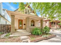 Charming bungalow features a quaint front porch and unique stone-accented columns and a beautiful stained glass front door at 3217 Irving St, Denver, CO 80211