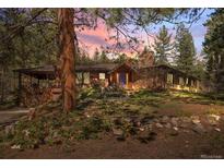 Charming home with stone accents, covered porch, mature trees, and a colorful front door at 9107 S Deer Creek Canyon Rd, Littleton, CO 80127