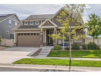 Charming two-story home featuring stone accents, neutral siding, a well-manicured lawn, and an attached two-car garage at 5495 Espana Ct, Denver, CO 80249