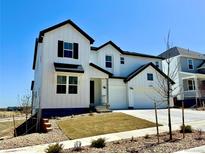 Beautiful two-story home featuring white siding, black accents, a manicured front lawn, and a two car garage at 9382 Quaker St, Arvada, CO 80007