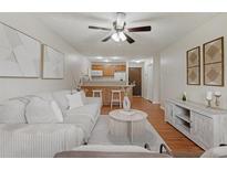 Bright living room featuring a ceiling fan, hardwood floors, and an open concept kitchen with breakfast bar at 9650 Huron St # 12, Thornton, CO 80260