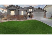 Charming home featuring a lush green lawn, stone accents, and an attached two car garage at 15961 Lookout Pt, Broomfield, CO 80023