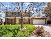 Charming two-story home features brick facade, green lawn and a beautiful mature tree at 978 Mercury Cir, Lone Tree, CO 80124