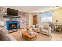 Cozy living room featuring a brick fireplace, hardwood floors, and comfortable seating arrangements at 155 S Pennsylvania St # 311, Denver, CO 80209
