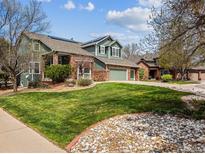 Beautiful two-story home with a well-maintained lawn, brick accents, and a two-car garage at 10029 Winterthur Ct, Highlands Ranch, CO 80129