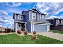 Charming two-story home featuring a two-car garage, manicured lawn, and a welcoming front entrance at 9571 Marmot Ridge Cir, Littleton, CO 80125