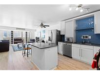 Bright, updated kitchen featuring stainless steel appliances, an island, and vibrant blue backsplash tiles at 1121 Albion St # 210, Denver, CO 80220