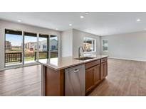 Bright, modern kitchen with island, stainless steel appliances, and sliding glass doors at 9972 Wheeling St, Commerce City, CO 80022