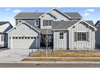 Beautiful two-story home featuring grey siding, a well-manicured lawn, and a two car garage at 16075 E 109Th Pl, Commerce City, CO 80022