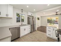 Bright kitchen boasts stainless steel appliances, white cabinetry, quartz countertops and modern tile flooring at 7691 Osage St, Denver, CO 80221