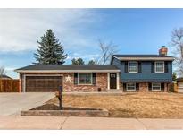 Charming split-level home with brick facade, blue siding, well-kept lawn, and attached two-car garage at 6111 W Maplewood Pl, Littleton, CO 80123