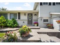 Charming front door with a wreath and well-manicured landscaping featuring colorful flowers and lush greenery at 7371 Otis Ct, Arvada, CO 80003