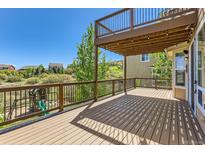 Large deck area with iron railing and shade from the upper deck overlooks a lush backyard at 1905 Graphite Ct, Castle Rock, CO 80108