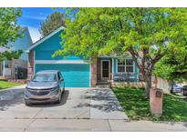 Charming exterior view of a two-story home with a lush green lawn and blue garage door at 12333 Newport Ct, Brighton, CO 80602