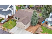 Aerial view of a two story tan home with a mature evergreen tree and a concrete driveway to a two car garage at 9960 Garland Ln, Broomfield, CO 80021