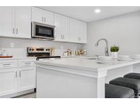Modern kitchen with white cabinets, quartz countertops, and island at 9300 Grove St, Westminster, CO 80031