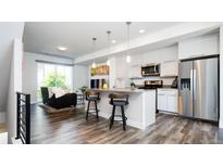 Bright, modern living space with open kitchen, bar seating, stainless appliances, and hardwood floors at 5630 W 11Th Pl, Lakewood, CO 80214