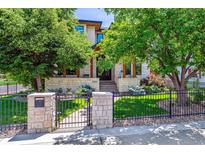 Charming home with stone accents, lush landscaping, and a wrought iron fence creating inviting curb appeal at 2600 S Adams St, Denver, CO 80210