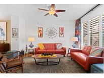 Bright living room features a ceiling fan, modern art, and an eye-catching red leather couch at 437 S Reed Ct, Lakewood, CO 80226