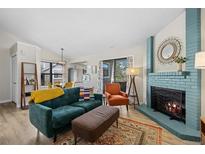 Bright living room featuring a blue fireplace, hardwood floors, and open access to the kitchen at 8378 S Upham Way # B305, Littleton, CO 80128