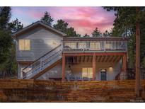 Charming home with a spacious deck and wooden fence, set against a backdrop of lush trees at 13495 Shiloh Rd, Conifer, CO 80433