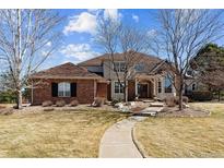 Charming brick home with a well-manicured lawn, mature trees, and a welcoming walkway to the front door at 391 High Ridge Way, Castle Pines, CO 80108