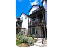 Modern townhome featuring brick accents and dark trim, plus balcony with seating area at 5189 Vivian St, Wheat Ridge, CO 80033