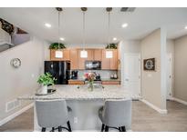 Bright kitchen features a granite island, stainless appliances, and wood cabinets at 13711 Ash Cir, Thornton, CO 80602