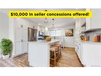 Bright kitchen with stainless steel appliances, white cabinetry and an island with barstool seating at 7818 Florado St, Denver, CO 80221