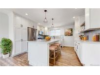 Bright kitchen with white cabinets, stainless steel appliances, and center island with seating at 7818 Florado St, Denver, CO 80221