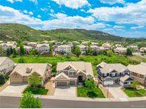 Beautiful aerial view of a neighborhood nestled against rolling green hills under a bright blue, partly cloudy sky at 5010 Persimmon Ln, Castle Rock, CO 80109