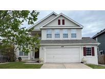Charming two-story home features an attached two car garage, manicured lawn, and decorative shutters at 8769 S Dudley St, Littleton, CO 80128