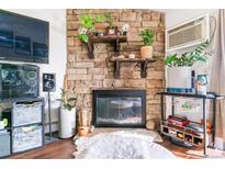 Cozy living room featuring a stone fireplace, wooden shelves, modern decor, and comfortable seating at 10150 E Virginia Ave # 19-303, Denver, CO 80247