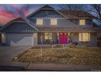 Charming home with a well-manicured lawn and a pink front door adorned with festive wreaths at 14223 W 1St Dr, Golden, CO 80401