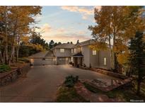 Beautiful home exterior with three-car garage, mature trees, and long driveway at 24768 Foothills N Dr, Golden, CO 80401