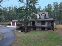 Charming two-story home with a spacious front porch and mature trees at 4305 Red Rock Dr, Larkspur, CO 80118