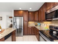 Well-lit kitchen features dark wood cabinets, granite countertops, and stainless steel appliances at 2363 Ranch Dr, Westminster, CO 80234