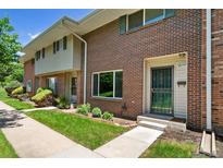 Inviting brick townhome featuring a well-maintained lawn and charming landscaping at 3806 S Yosemite St, Denver, CO 80237