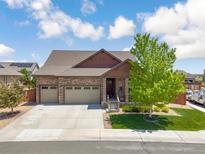 Beautiful two-story home with a three-car garage and a well-manicured lawn and mature trees under a partly cloudy sky at 15804 Elizabeth E Cir, Thornton, CO 80602
