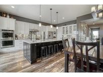 Spacious kitchen with white cabinets, dark island, granite countertops, and wood floors at 15804 Elizabeth E Cir, Thornton, CO 80602