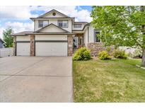 Charming two-story home featuring a three-car garage, stone accents, lush lawn and mature trees at 5286 Rustic Ave, Firestone, CO 80504