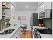 Modern kitchen features white cabinetry, stainless steel appliances, and a dining area at 7615 E Quincy Ave # 103, Denver, CO 80237