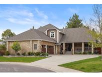 Beautiful home featuring a stone exterior, well-manicured lawn, mature trees, and a three car garage at 7836 S Fairfax Ct, Centennial, CO 80122