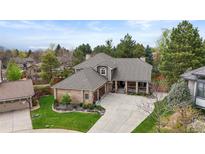 Stunning home exterior with brick accents, mature trees, and a well-manicured front yard at 7836 S Fairfax Ct, Centennial, CO 80122