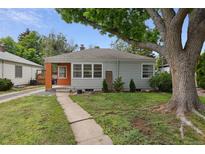 Charming single-story home with a gray exterior, orange entryway, and mature tree shading the front yard at 2709 S Franklin St, Denver, CO 80210