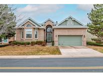 Charming single-Gathering brick home with an attached two-car garage and manicured front yard at 87 Canongate Ln, Highlands Ranch, CO 80130
